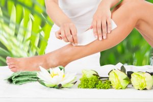 Beautician Waxing Woman's Leg In Spa